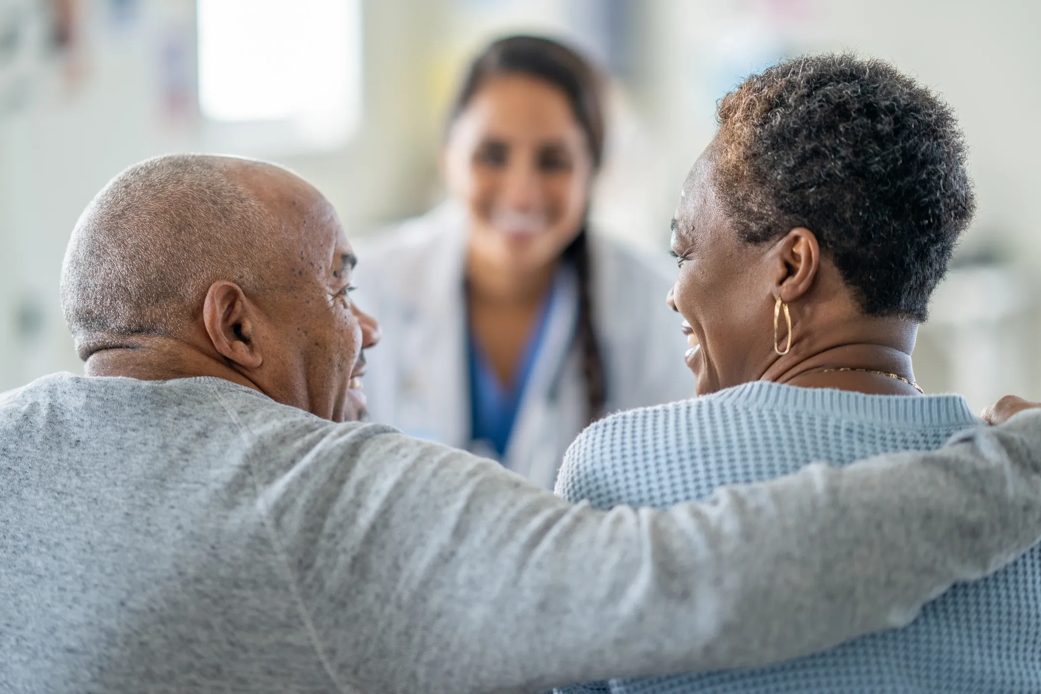 Couple smiling with doctor in background.