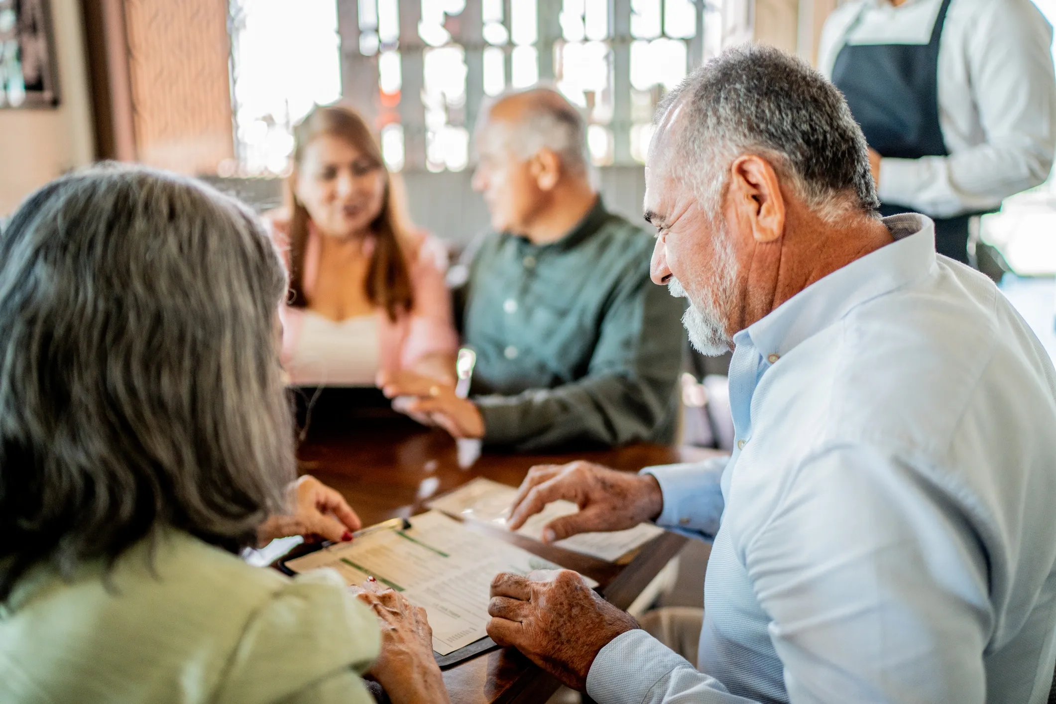 Elderly couples dining at a restaurant table.